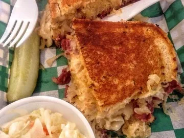 A classic Reuben sandwich piled high with thinly sliced corned beef, tangy sauerkraut, melted Swiss cheese, and creamy Russian dressing, all grilled to perfection on rye bread.