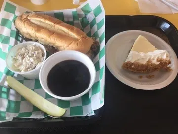 A French Dip sandwich with tender, thinly sliced roast beef piled on a warm, toasted baguette, served alongside a flavorful bowl of au jus for dipping.