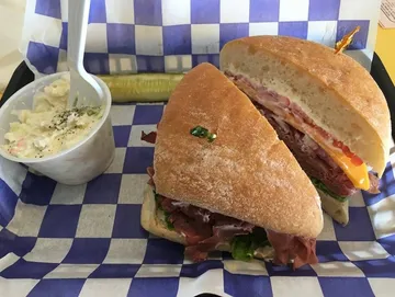 A roast beef and cheddar sandwich featuring layers of tender, thinly sliced roast beef topped with melted cheddar cheese, served on a toasted bun.